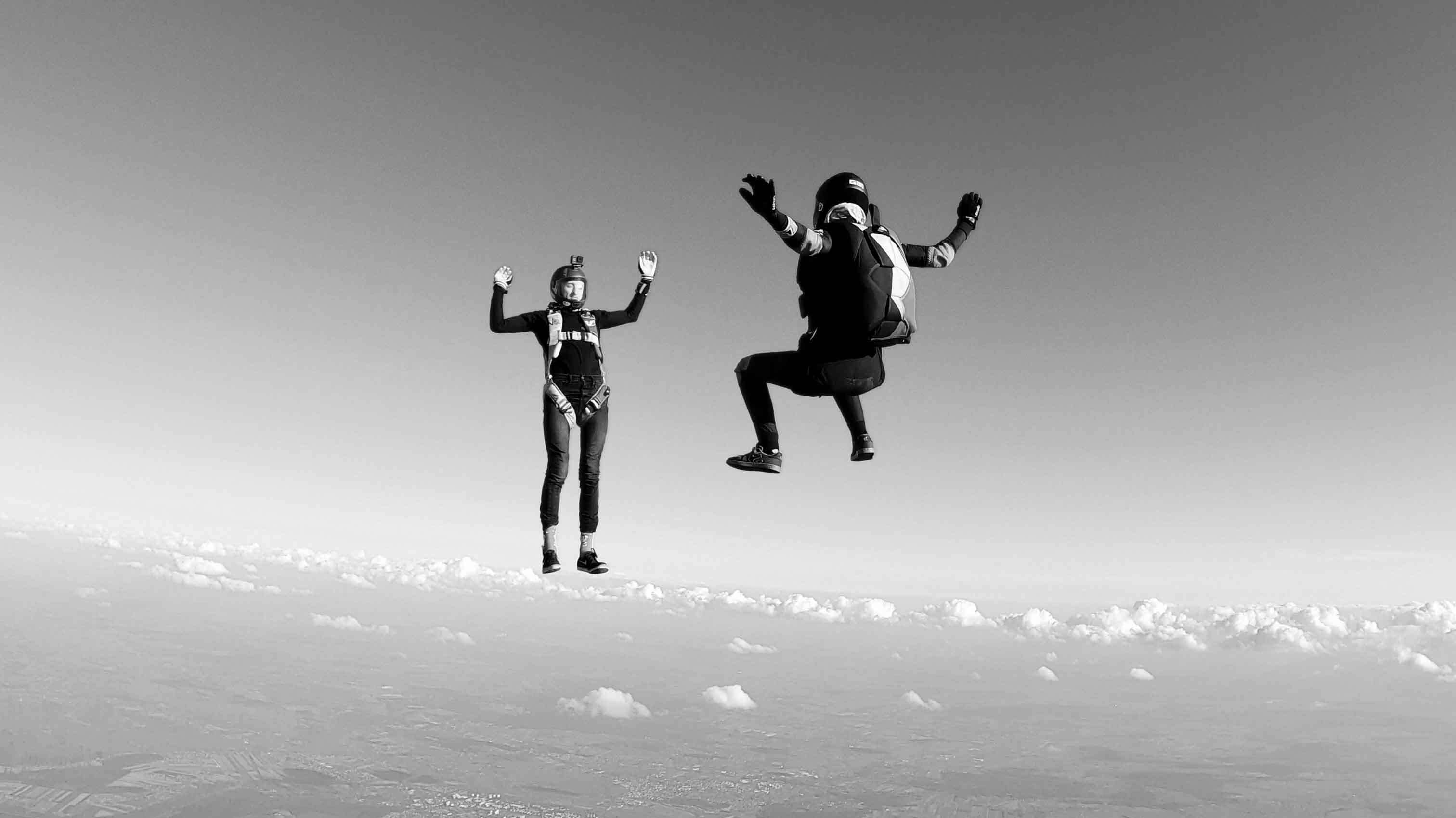 black and white image of two people skydiving