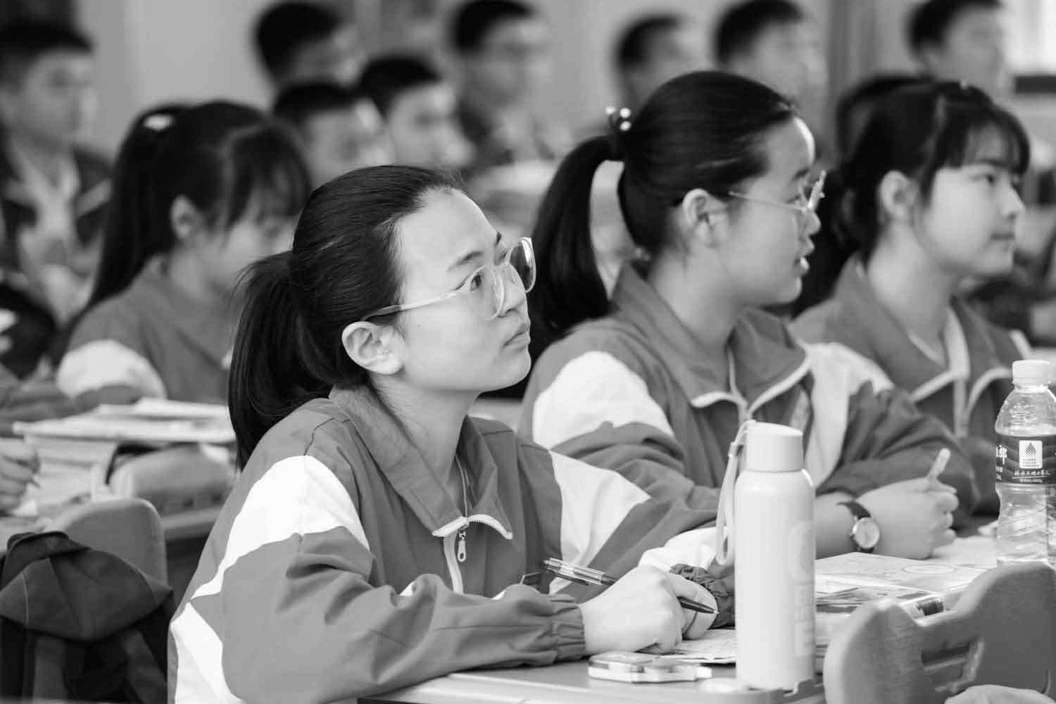 black and white image of students studying all wearing same uniform looking up in same direction