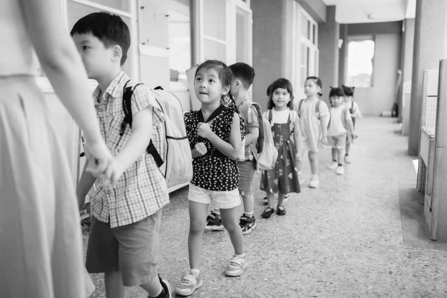 black and white image of young children lining up holding hands