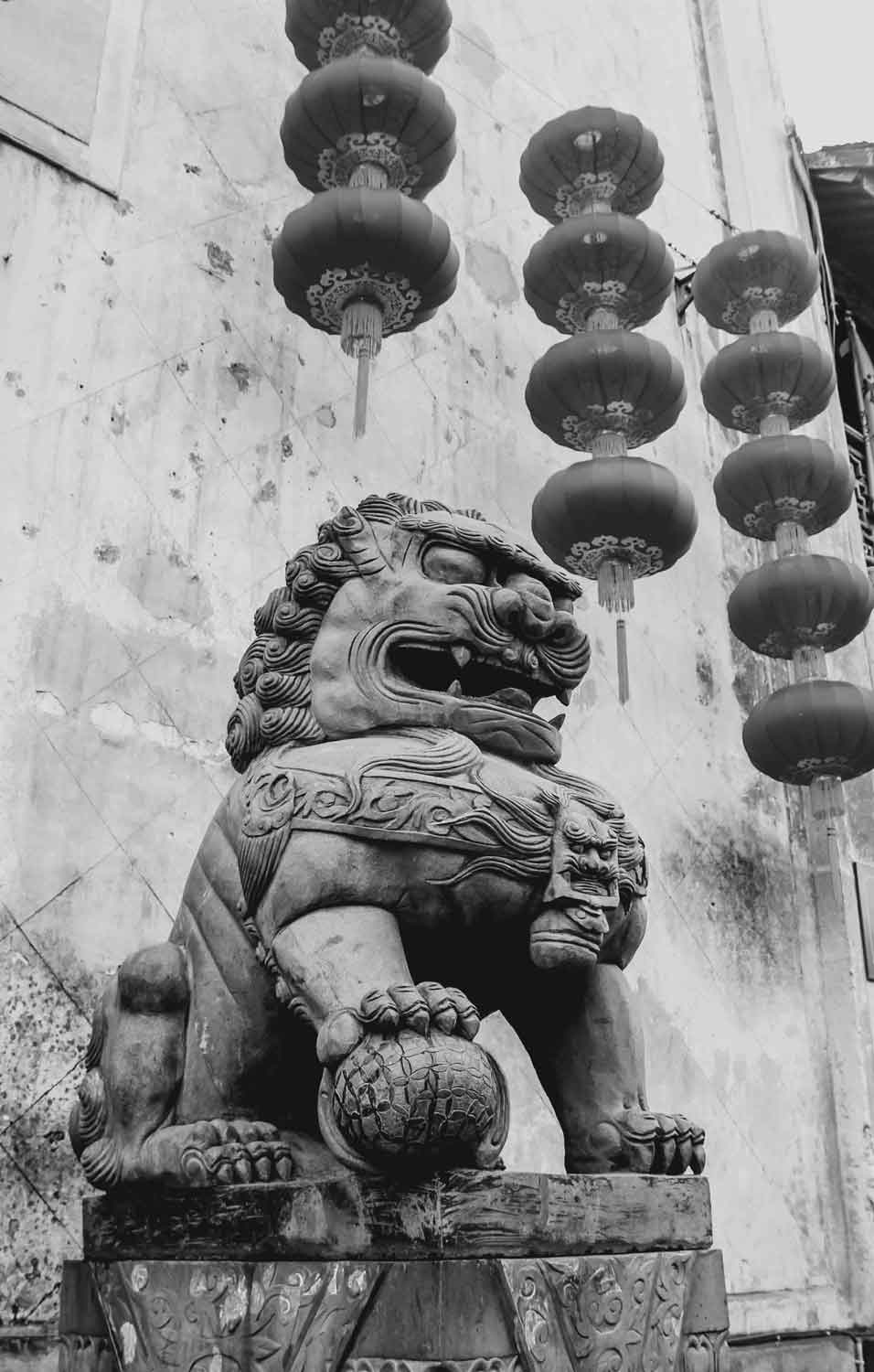 black and white image of dragon statue with lanterns hanging in background