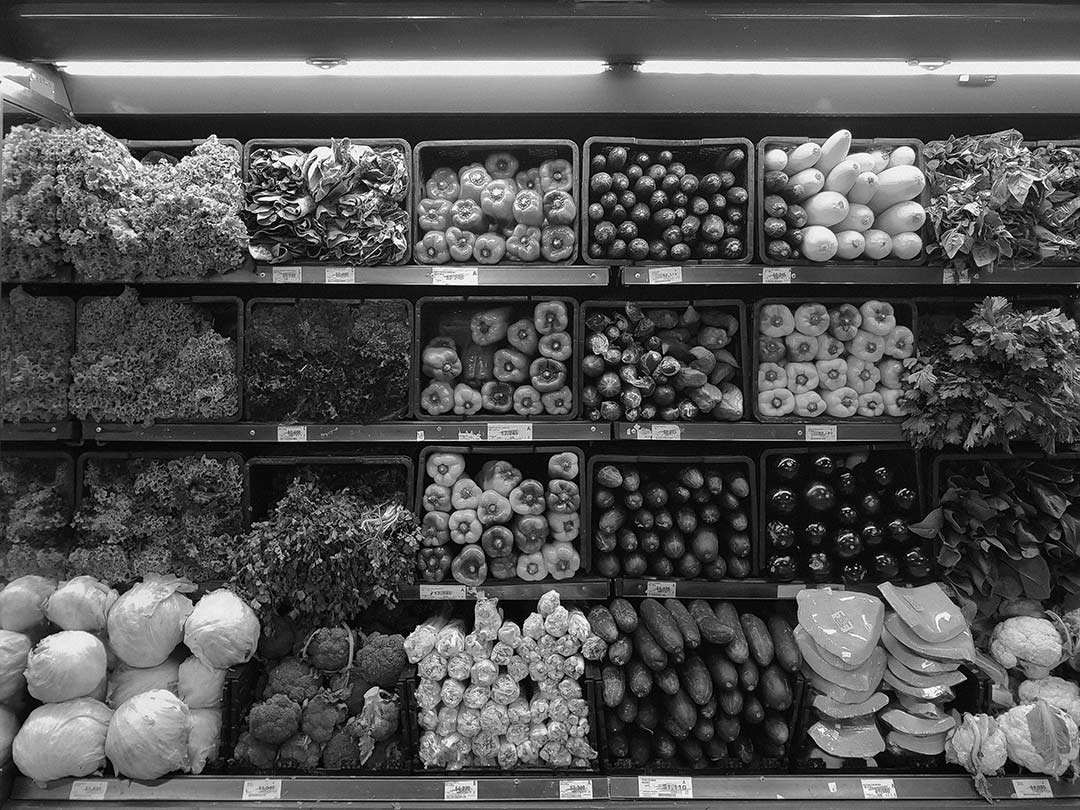 black and white photo of fruit and vegetables all lined up in boxes