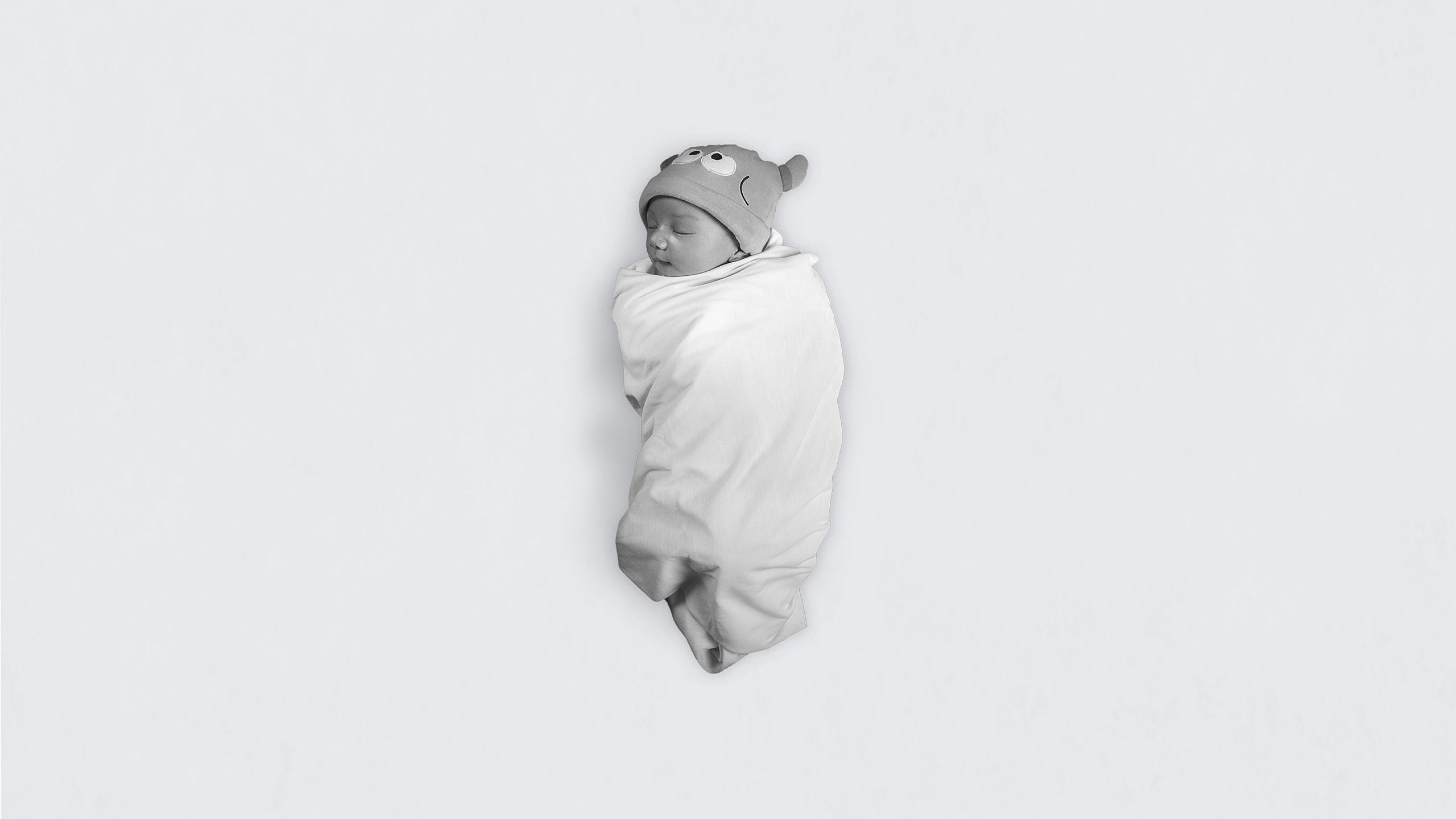 black and white image of baby named Meydi wrapped up in a cloth with a beanie on