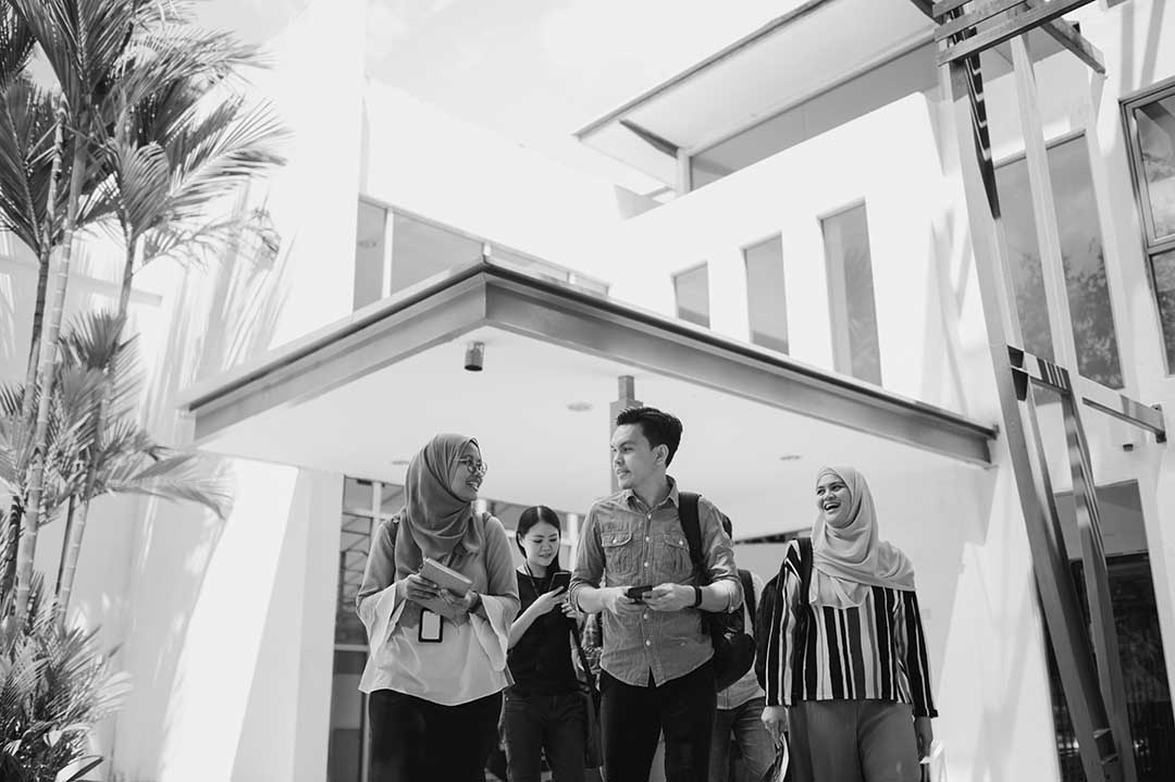 black and white image of group of people walking from building talking and smiling