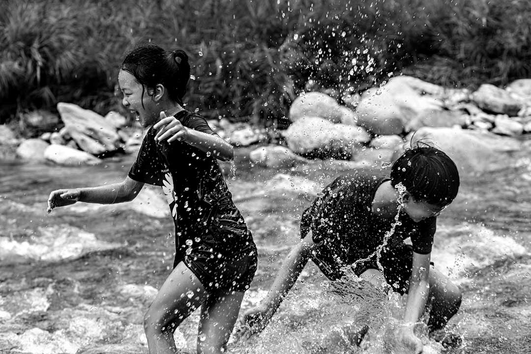 black and white image of two children playing and splashing in river