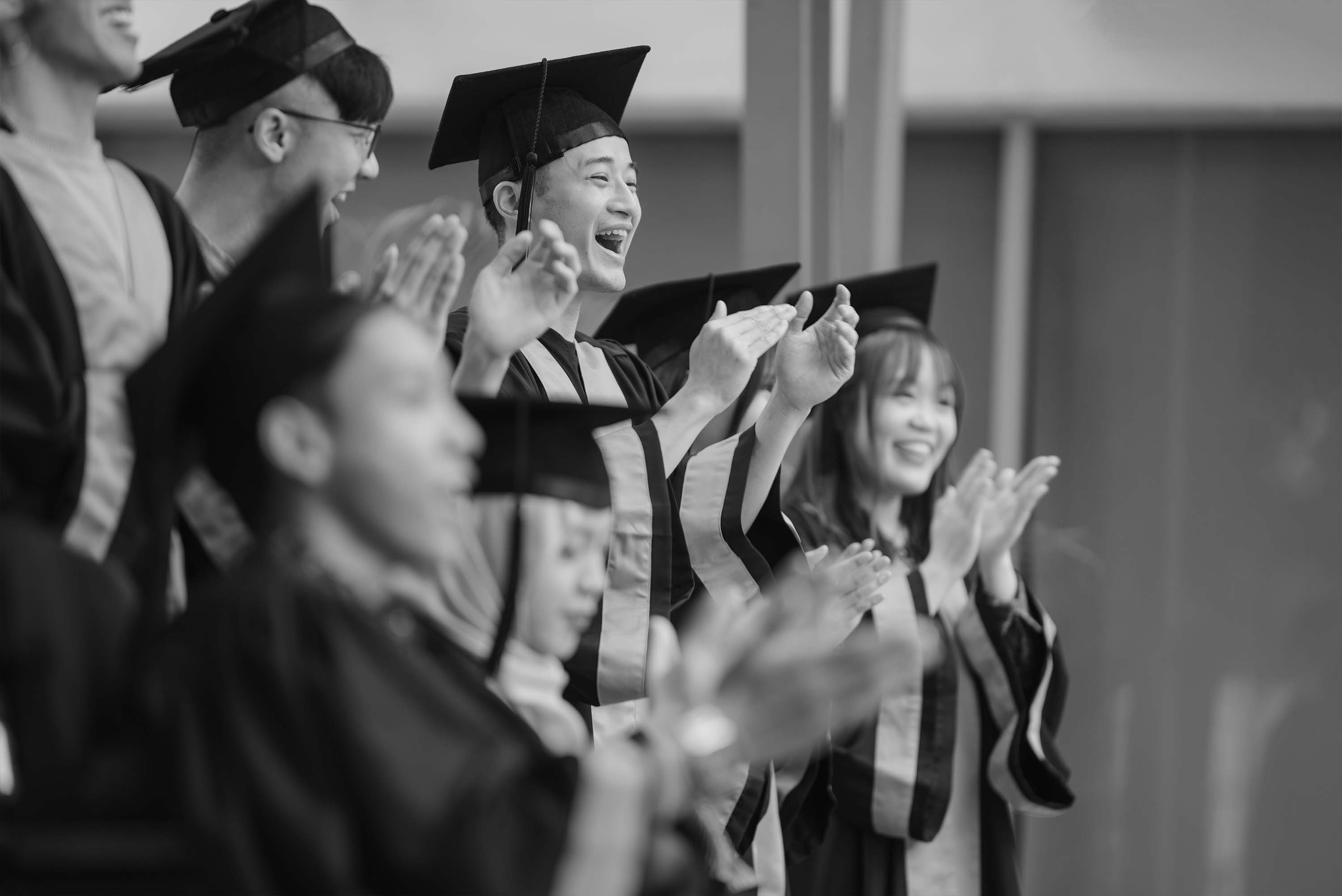 Black and white photo of a group of students graduating with gown and caps on