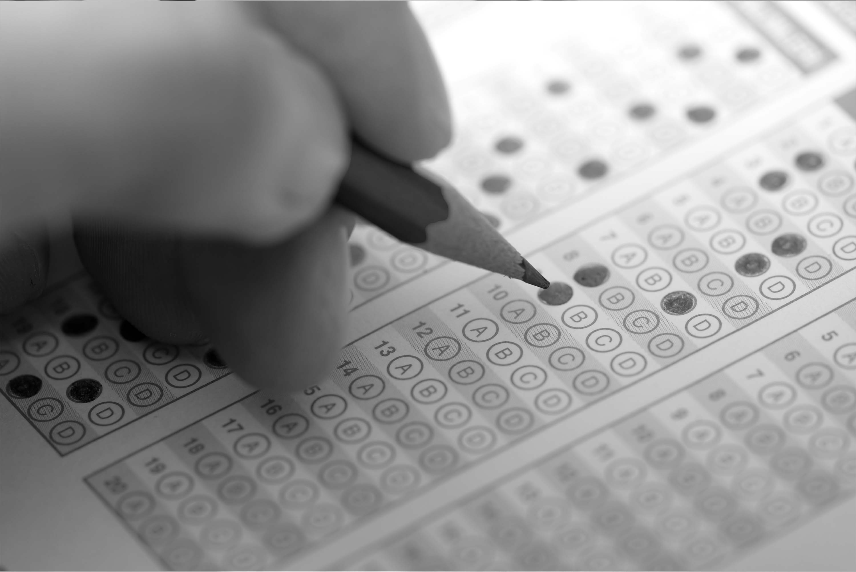 black and white image of a exam card being marked with a pencil
