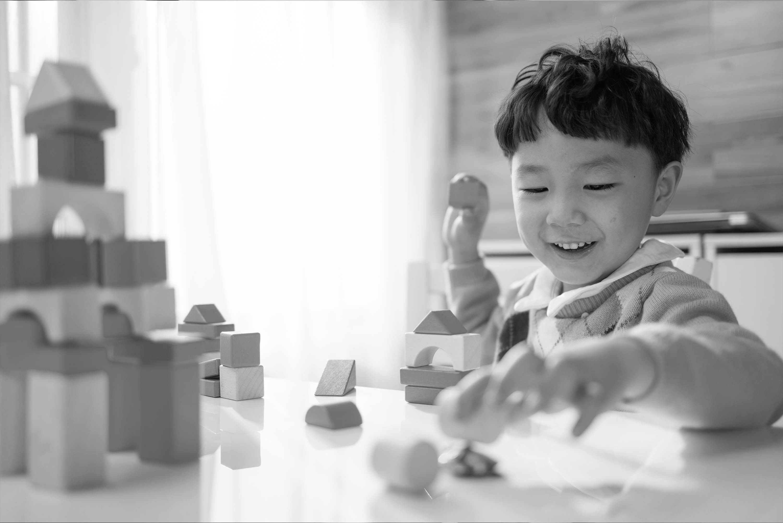 black and white image of young child playing with blocks in a childcare setting