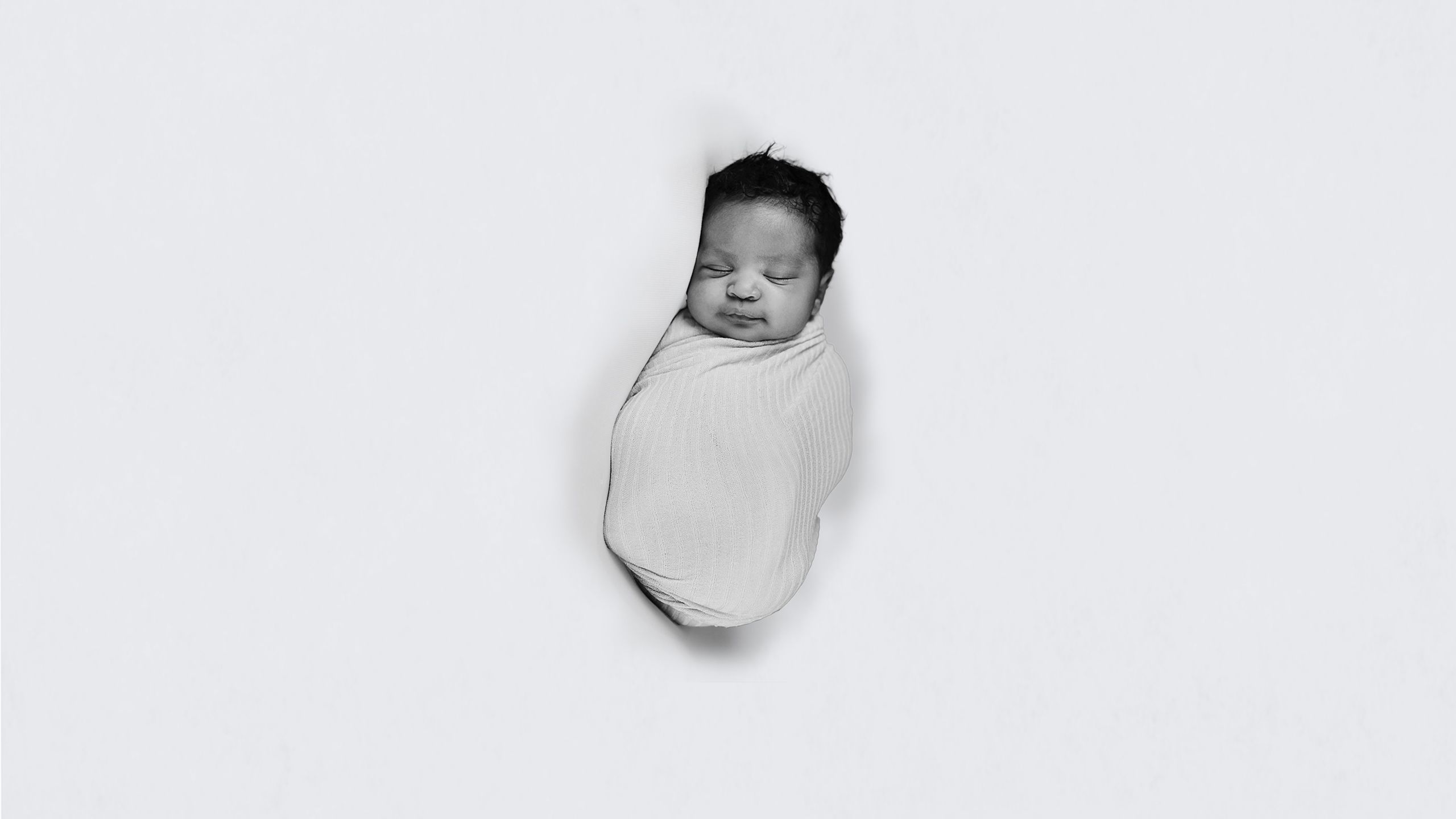 black and white photo of a baby named samroze wrapped in a white blanket