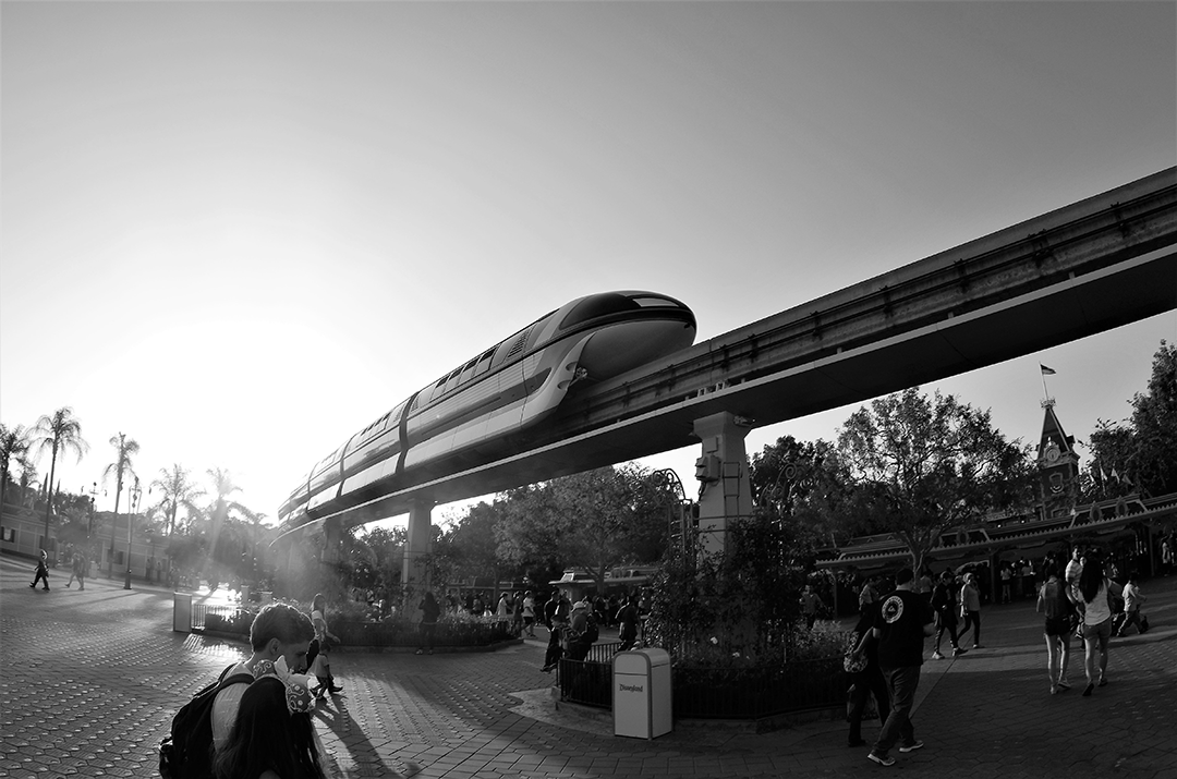 black and white image of a train monorail above a city street