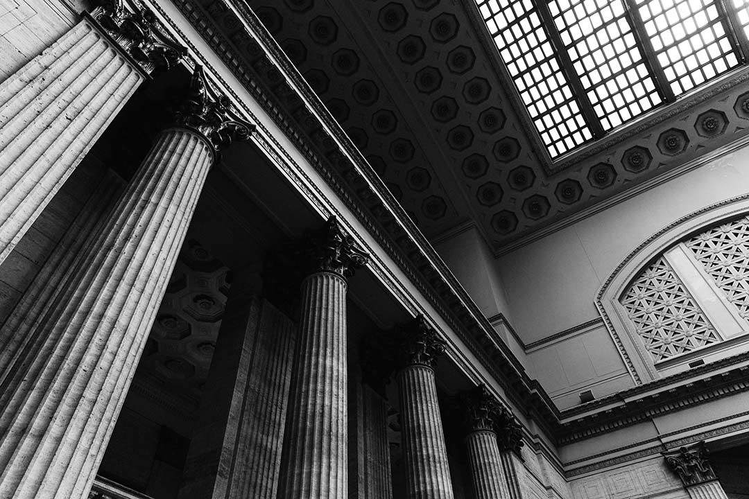 black and white image of a interior building with large grand pillars 