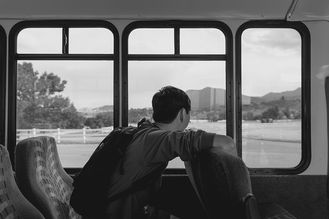 black and white image of samroze sitting in a bus looking out the window to mountains