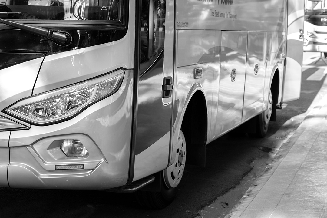 black and white image of a bus pulled up to a street curb