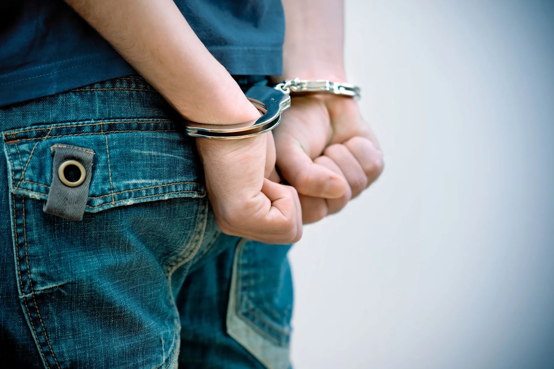 A child with their hands in handcuffs with their hands behind their back