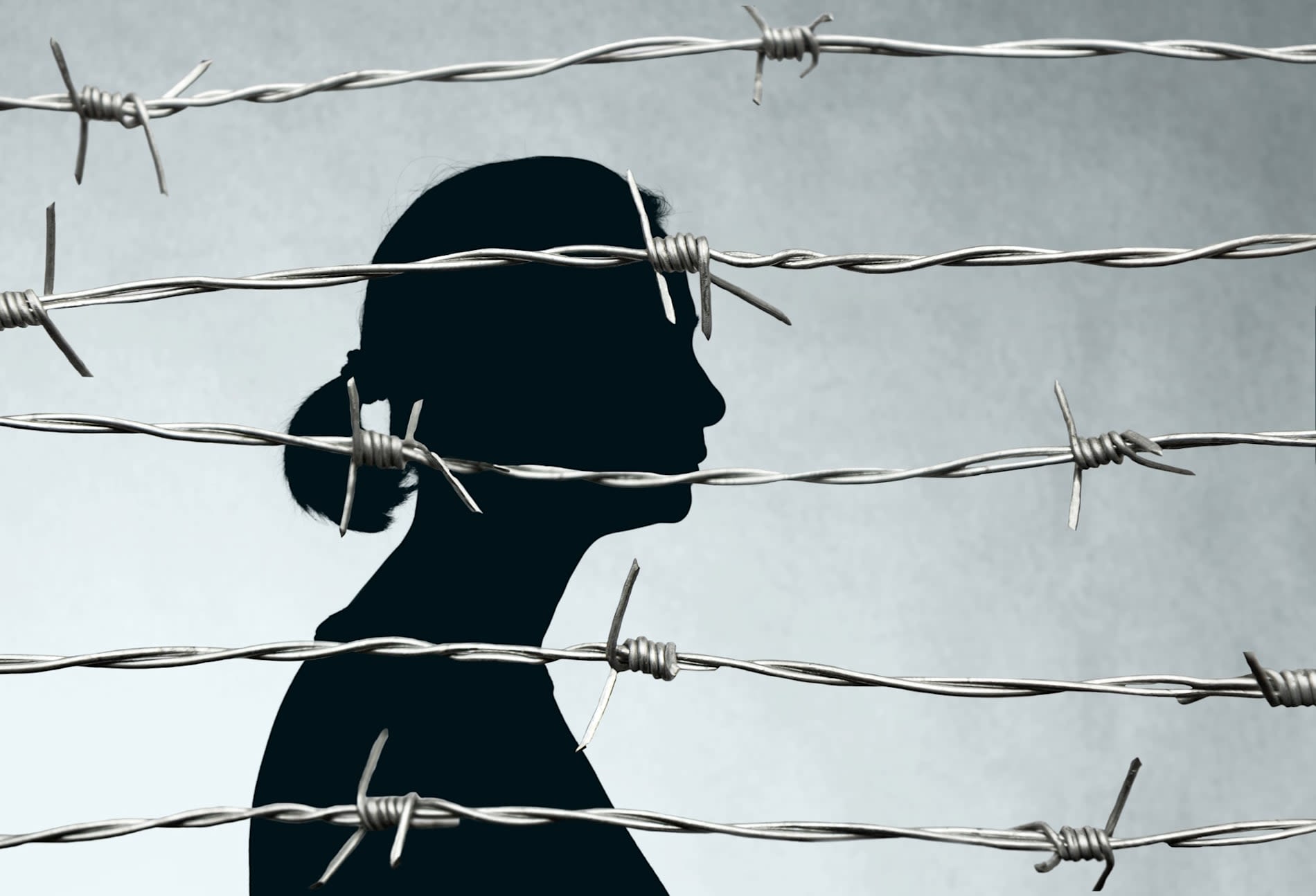 A photo-illustration of a woman's silhouette behind barbed wire on a grey stone background.