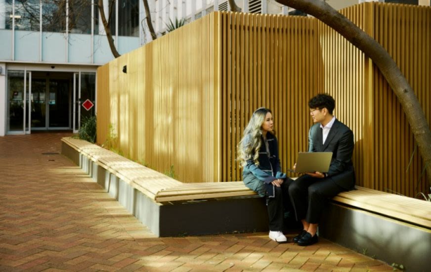 A man and woman talking to each other whilst looking at a laptop